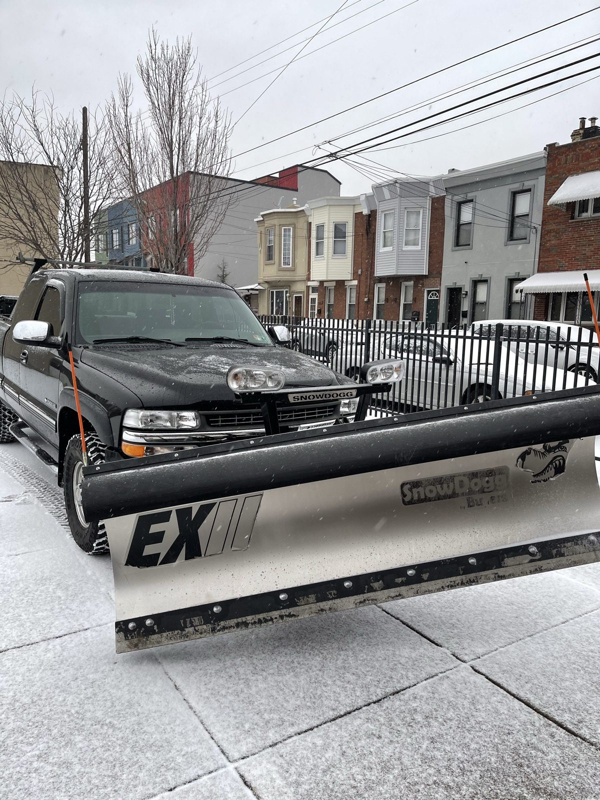 JD Home Construction SnowDogg plow truck clearing a residential street during an active snowstorm